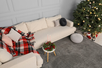 Beautiful Christmas tree, sofa and candles on table in living room