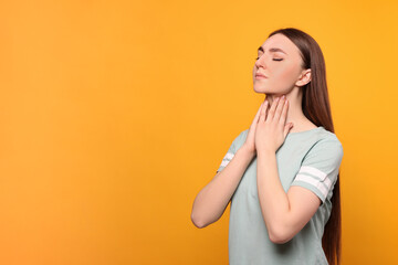 Young woman with sore throat on orange background. Space for text