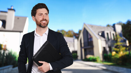 Smiling real estate agent with portfolio outdoors, space for text. Beautiful houses on street