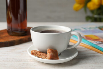 Cup of aromatic coffee, caramel candies and syrup on white wooden table