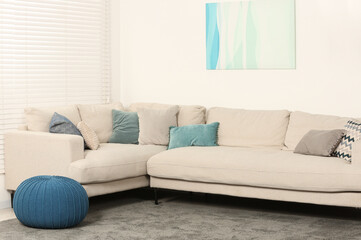 Stylish room with soft sofa, pillows and ottoman. Interior design