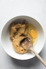 Churros dough and egg in a white bowl, choux pastry dough about to be fried, process of making churros