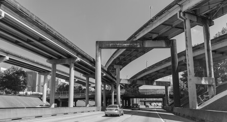 Driving on Texas highways with overpasses and underpasses, trees around, cars, and buildings on the left. 