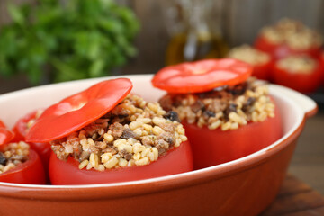 Delicious stuffed tomatoes with minced beef, bulgur and mushrooms in baking dish, closeup