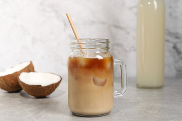 Mason jar of delicious iced coffee with coconut syrup on light grey table