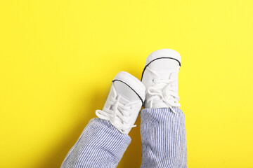 Little baby in stylish gumshoes on yellow background, top view