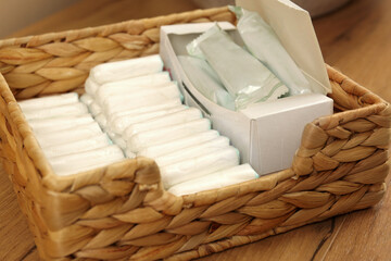 Fototapeta na wymiar Many different tampons in wicker basket on wooden table, closeup. Menstrual hygienic product