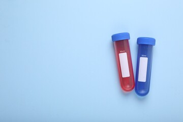 Test tubes with colorful liquids on light blue background, flat lay and space for text. Kids chemical experiment set