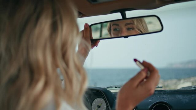 Woman looking makeup car mirror enjoying reflection sensual red lips close up. 