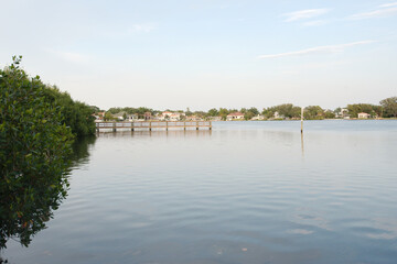 Wide angle view Coffee Pot Bay in Saint Petersburg, FL.  Wood Pier in the background. Sunny day with blue sky and calm water. With green trees.