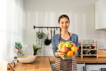 Obraz premium Portrait of Asian young woman hold a bowl of fruits and look at camera. 