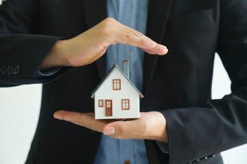 Close up real estate agent holding house model for consult the client.