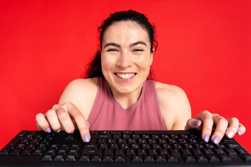 Smiling caucasian woman typing on keyboard shopping online with sales, ordering food isolated on red background. Excited successful freelancer working online, technology concept