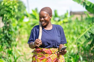 excited image of young african lady in a farm holding smart phone- black lady in maize farm