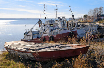 Old fishing ships and a boat on the bank of the Ob river near the village in summer