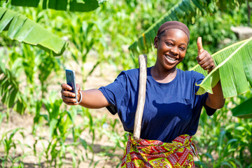 image of beautiful african lady with smartphone in garden- thumbs up image of cheerful black girl...