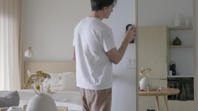 Man Decreasing the Room Temperature with Wall Mounted Smart Thermostat