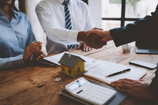 Real Estate Agent Or Sales Manager Shaking Hands With Client Couple After Selling Home And Agreeing To Sign Home Purchase And Insurance Contract After Sales Service Concept.