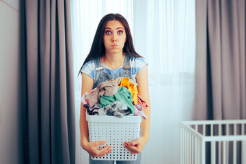 
Tired Mom Holding a Basket of Dirty Laundry in Nursery Room. Unhappy housewife doing home chores all day long
 - obrazy, fototapety, plakaty