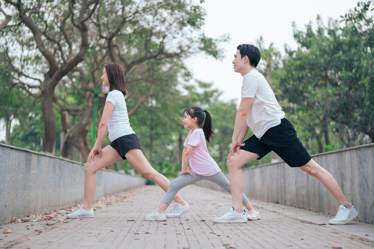 photo of young Asian family exercise at park
