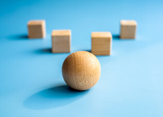 Wood sphere, different shape stand in front of the wooden cube blocks on blue background. Concept...