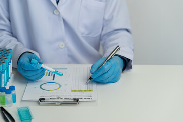 Male scientist using scientific test tubes with data recording of chemicals or drugs tested and examined by microscope in science laboratory for medicine biotechnology biology.