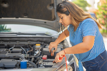 Obraz na płótnie Canvas Woman trying to fix her battery-less car