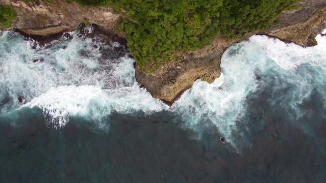 Aerial, dynamic Movement of ocean water, raging choppy waves pounding against steep cliff in a boiling-like motion causing white water foam.
Hydraulic action or coastal erosion. Nusa Penida Island