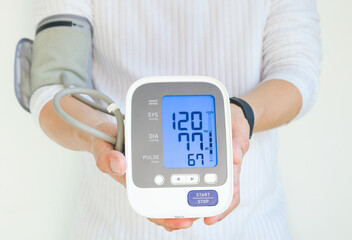 Man checks blood pressure monitor and heart rate monitor with digital pressure gauge. Health care and Medical concept. - obrazy, fototapety, plakaty
