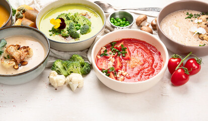Composition with various soups, ingredients and space for text on white background. Healthy food.