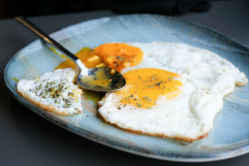 Fried eggs and spoon on plate 