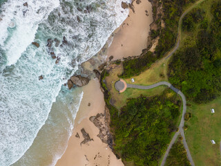 Aerial view of beach with caves and wavy path to lookout