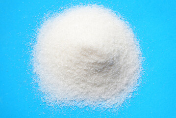 heap of sugar on blue background, white sugar for food and sweets dessert candy heap of sweet sugar crystalline granulated