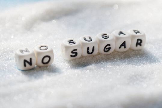 no sugar text blocks with white sugar on wooden background, suggesting dieting and eat less sugar for health