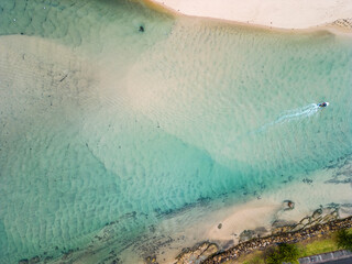 Aerial view of white sandy beach with boat passing