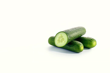 A pile of fresh whole and sliced green cucumbers isolated on white background with copy space. Created with Generative AI Technology