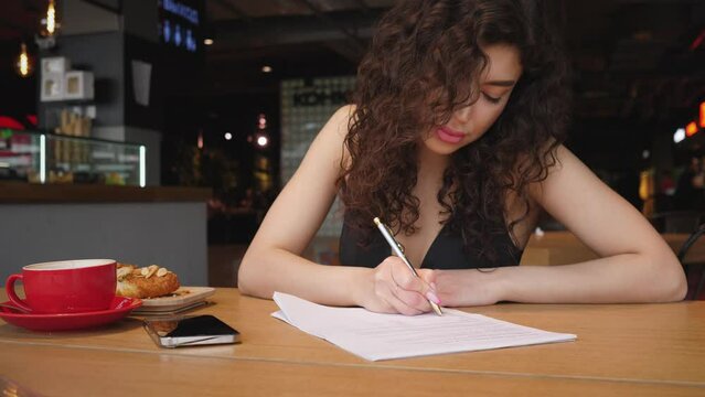 young beautiful woman filling out a resume in a cafe 4k