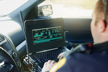 Database, laptop and a police officer in a car for security, urban law and safety data while...