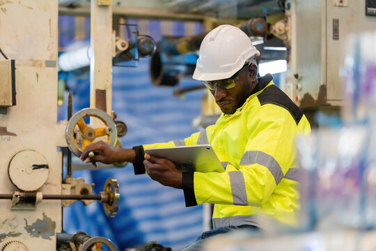 african engineer Controlling work via tablet Wear uniforms and helmets. Operates a hand crank machine while working on steel and plastic production. working in an industrial factory