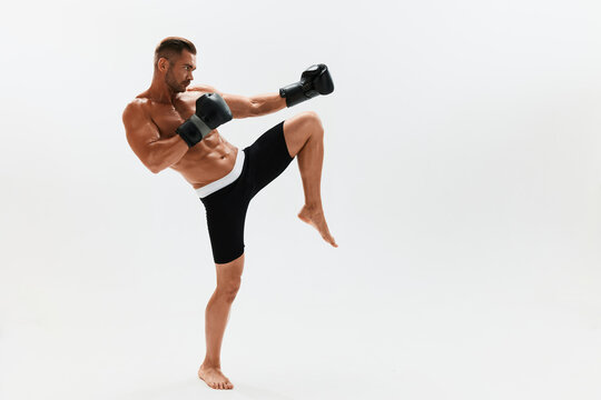 Man athletic bodybuilder poses in boxing gloves with nude torso abs in full-length background, boxing and martial arts. Advertising, sports, active lifestyle, light, competition, challenge concept. © SHOTPRIME STUDIO