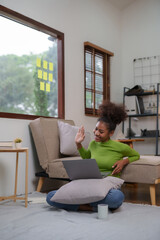 Happy young woman student having video call on laptop computer at home.  Young black female chatting online in social networks, having fun.