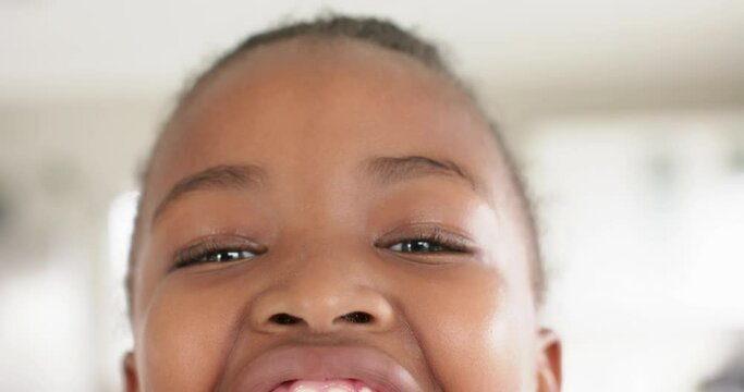 Portrait close up of happy african american girl looking at camera and smiling, in slow motion