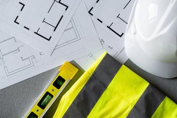 Home floor plans or building blueprint project, high-visibility clothing safety vest, spirit level and hard hat helmet for architect, construction worker, engineer contractor or interior designer.