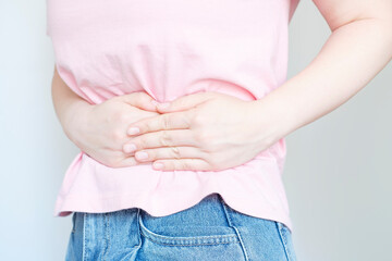 Female hands squeeze the stomach on white background, the concept of abdominal pain.