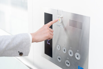 エレベーターの緊急呼び出しボタンを押してSOSを出す男性の手元