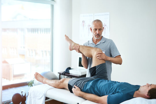 Legs, physiotherapist and patient with consultation, healthcare and stretching for recovery. Male person, men and chiropractor with a client, physical therapy and healing with rehabilitation and care - Powered by Adobe