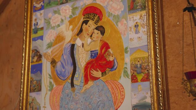 Icon of the mother of God with the baby Jesus in her arms in a gold frame and a lamp on the wall