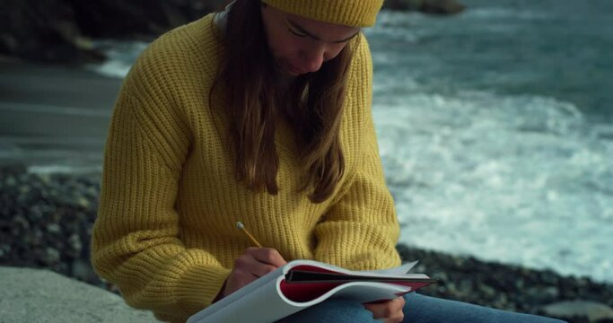 Portrait of a Focused Woman Writing on a Notebook by the Sea on an Autumn Day. Inspired Female Enjoying the Waves and Calming Scenery, Being Creative, Creating a Draft for her Next Book of Poetry