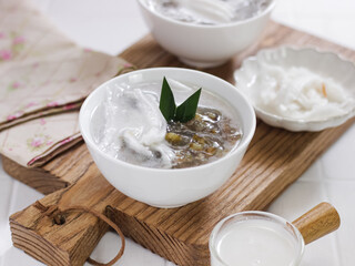 Es bubur kacang hijau or Green bean porridge ice with young coconut shavings. Served in white bowl, selective focus