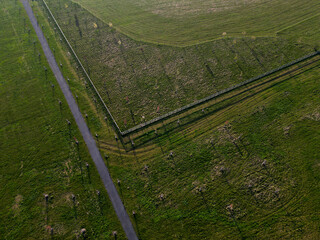 fly over the newly composed parkland with biocorridors and a horse enclosure. trees planted along the roads, in a giant circle over which a quality control plane flies.  composition can only enjoy